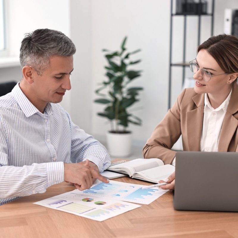 Banker working with client at wooden table in office